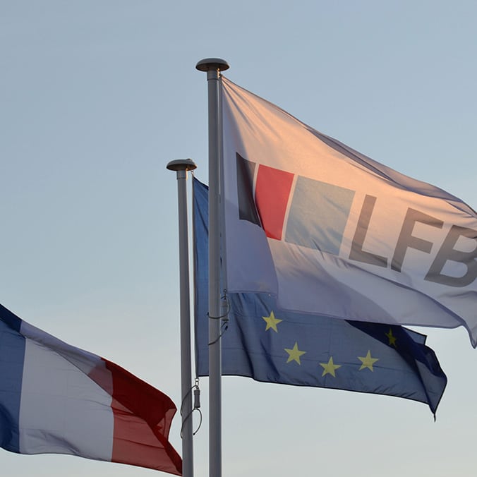 Three flags flying in the wind: the LFB flag, the European Union flag and the French flag.