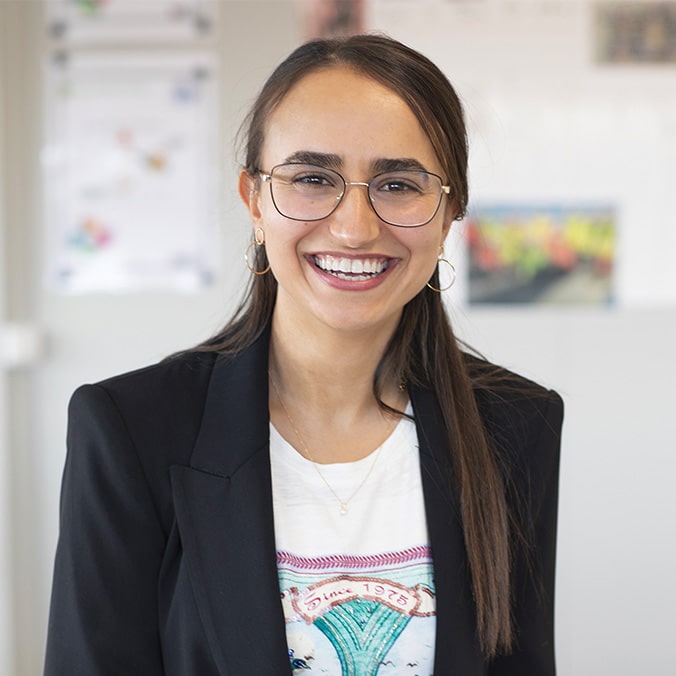 A young dark-haired woman with glasses smiles.