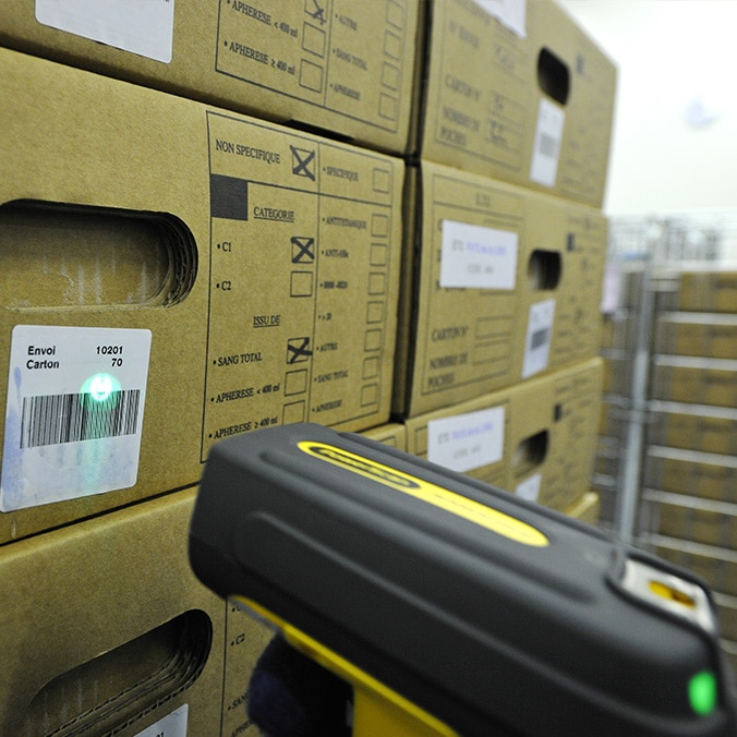 A scanner scans a barcode on a carton in a storage room.